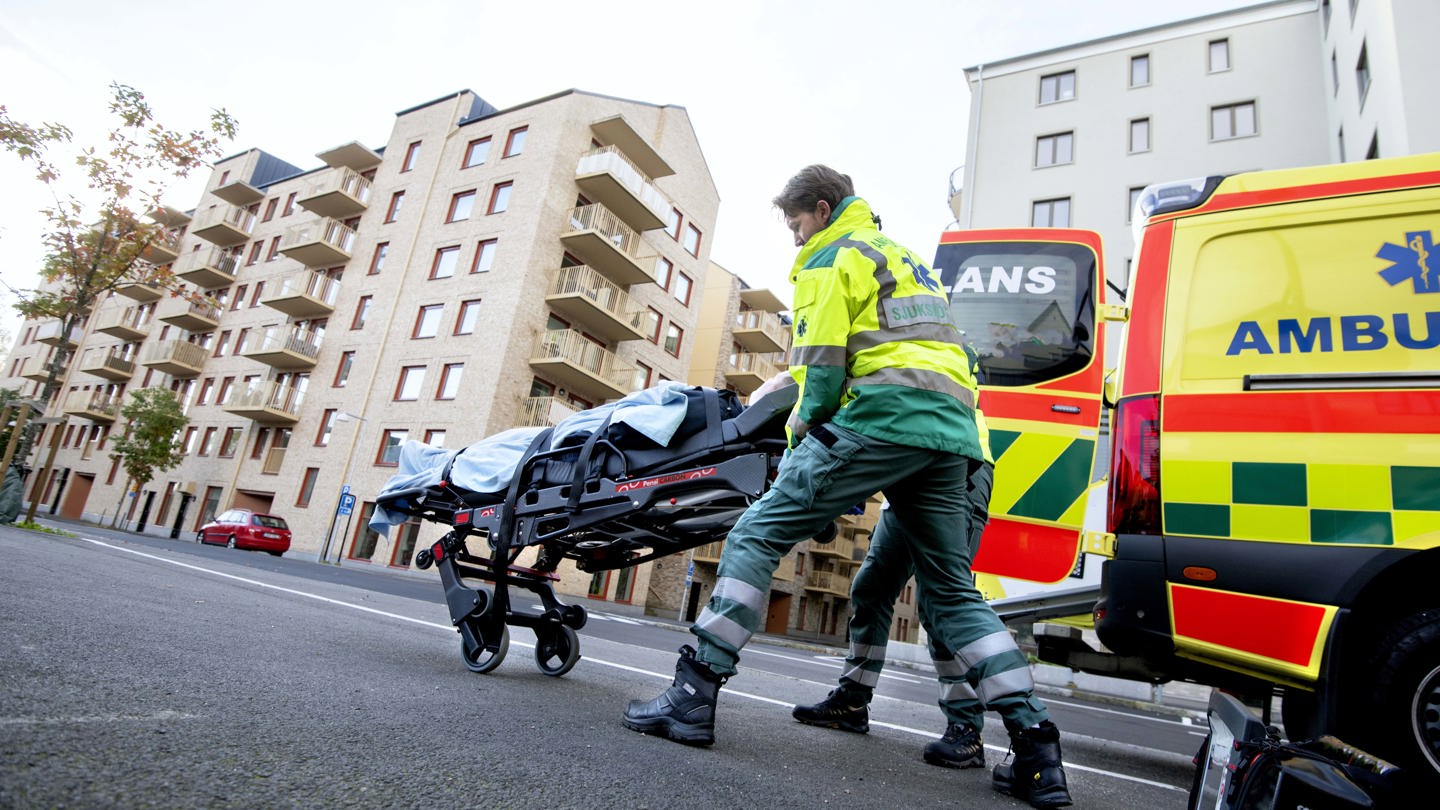 Ambulanspersonal utanför en ambulans med bår