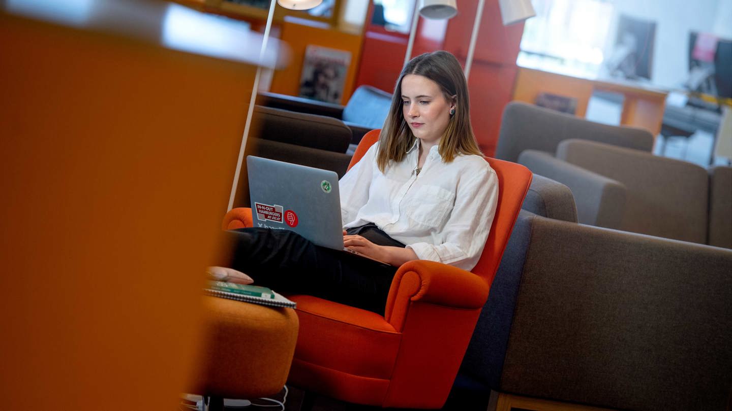 Student på campus med dator i knät